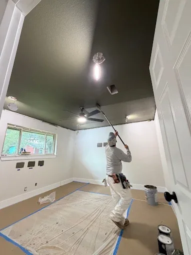 Painter applies a fresh coat to a protected interior room.