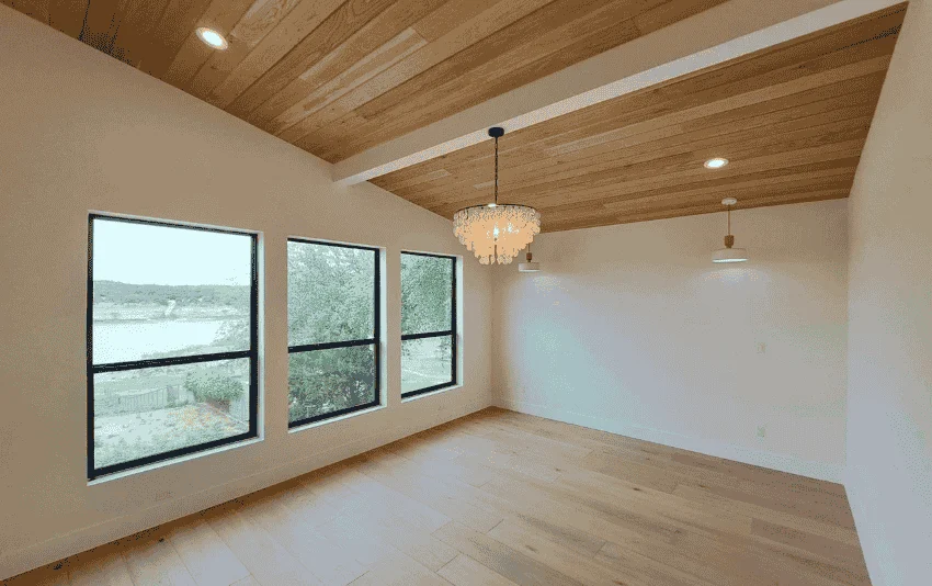 Light-painted room with a wood ceiling, large windows and a chandelier.