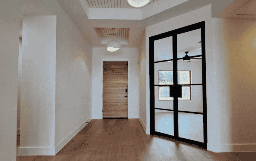 Painted entry hall with white trim and a black-framed glass door.