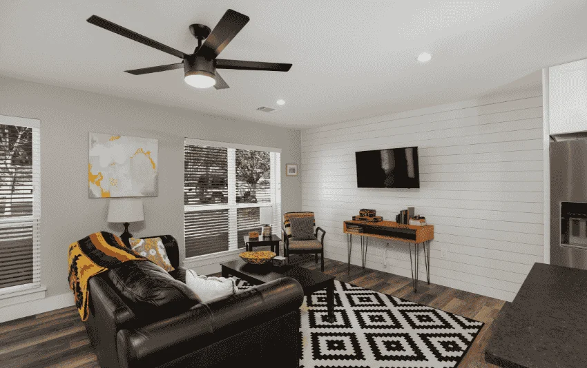 Furnished living room with light walls, a ceiling fan and patterned rug.
